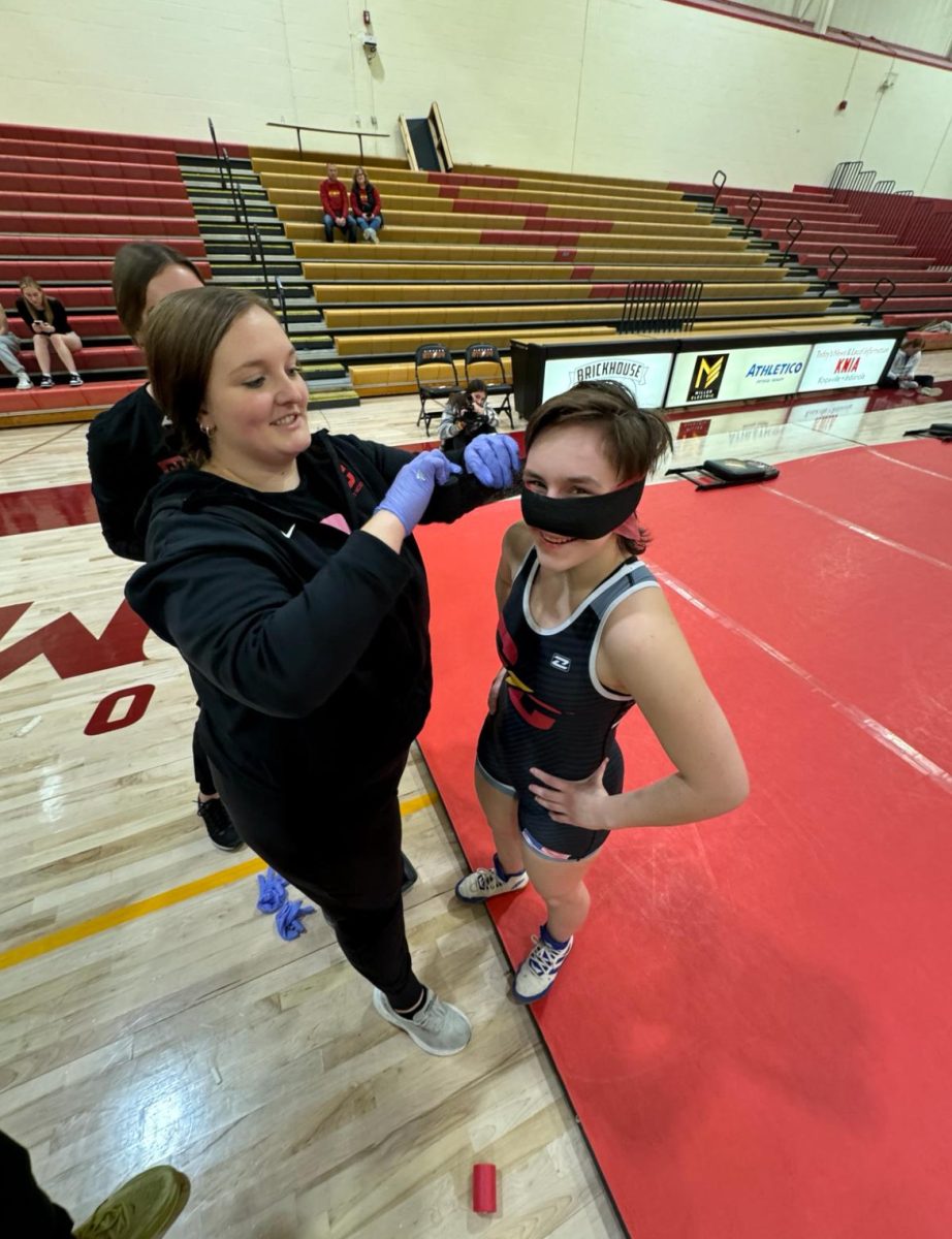 Assistant+Athletic+Trainer%2C+Kayley+Weiland%2C+attempts+to+stop+Ashley+Cannon%E2%80%99s+nosebleed+so+she+can+go+back+out+to+pin+her+opponent+contributing+to+Simpson%E2%80%99s+historical+win+over+Cornell+College.