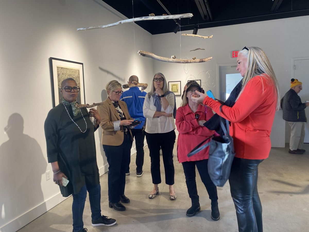 Artist, Jean-Marie Salem (left) explains her sculpture to her friends who surprised her at the gallery presentation. Salem’s work revolves around her race and she implements balance and illusions into her sculptures. 