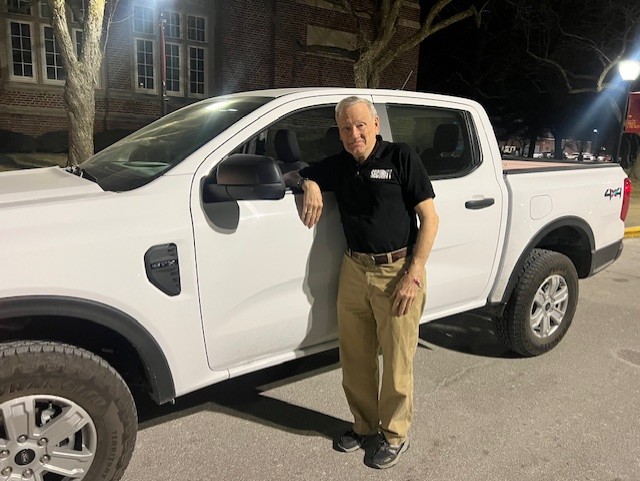 Evening campus security guard Russell Rivers next to his security vehicle.