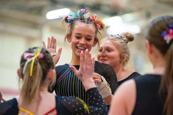 Junior Emma Tolbert celebrates with her teammates after her record-breaking floor routine.